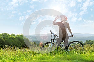Â Sport bike woman , drinking on a meadow , beautiful landscape